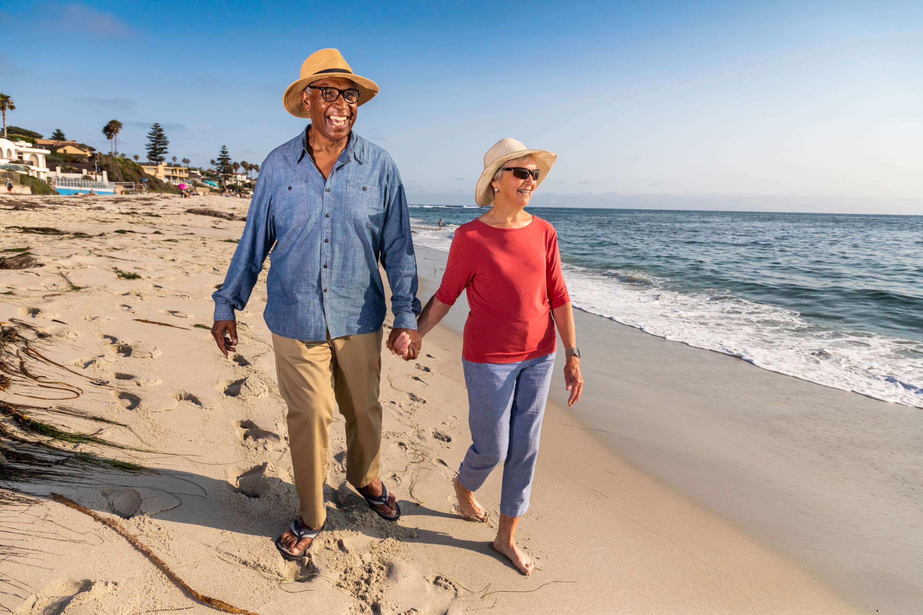 Woman and man walking along the beach while holding hands